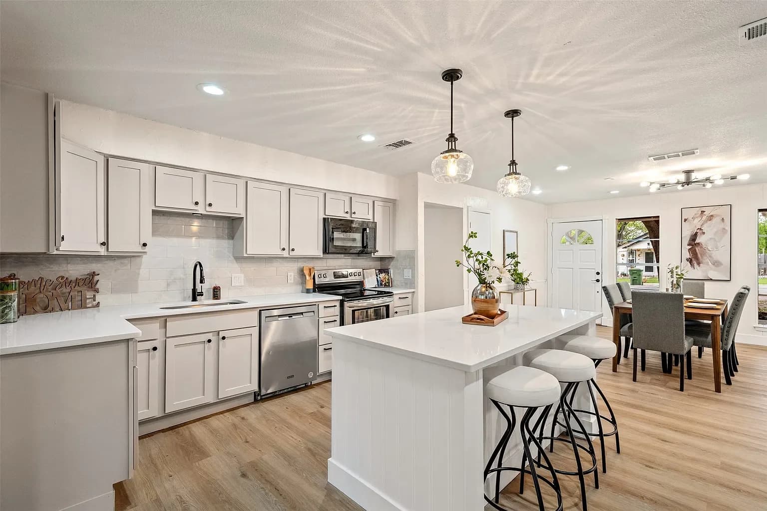 Remodelled kitchen with a quartz island, shaker cabinetry, and a tiled backsplash opening onto the dining room
